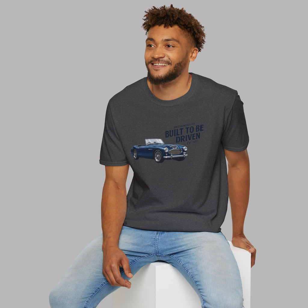 Man wearing a dark heather t-shirt with vintage design sitting on a white stool against a gray background
