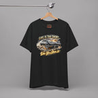 Black t-shirt with classic car graphic design and text hanging on a gray background