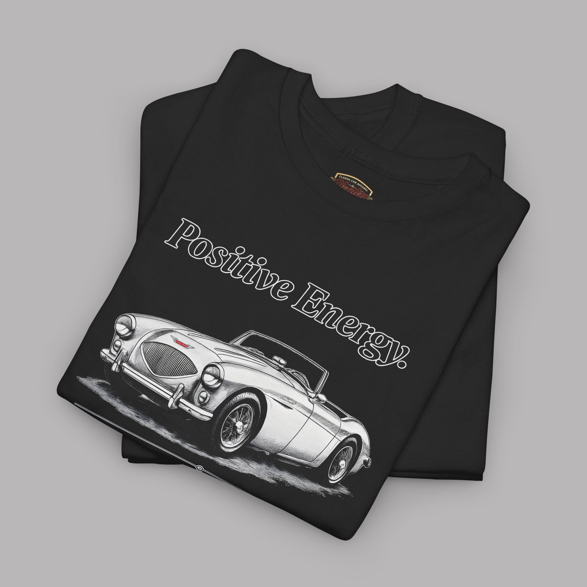 Folded black t-shirt with classic car design on a gray background