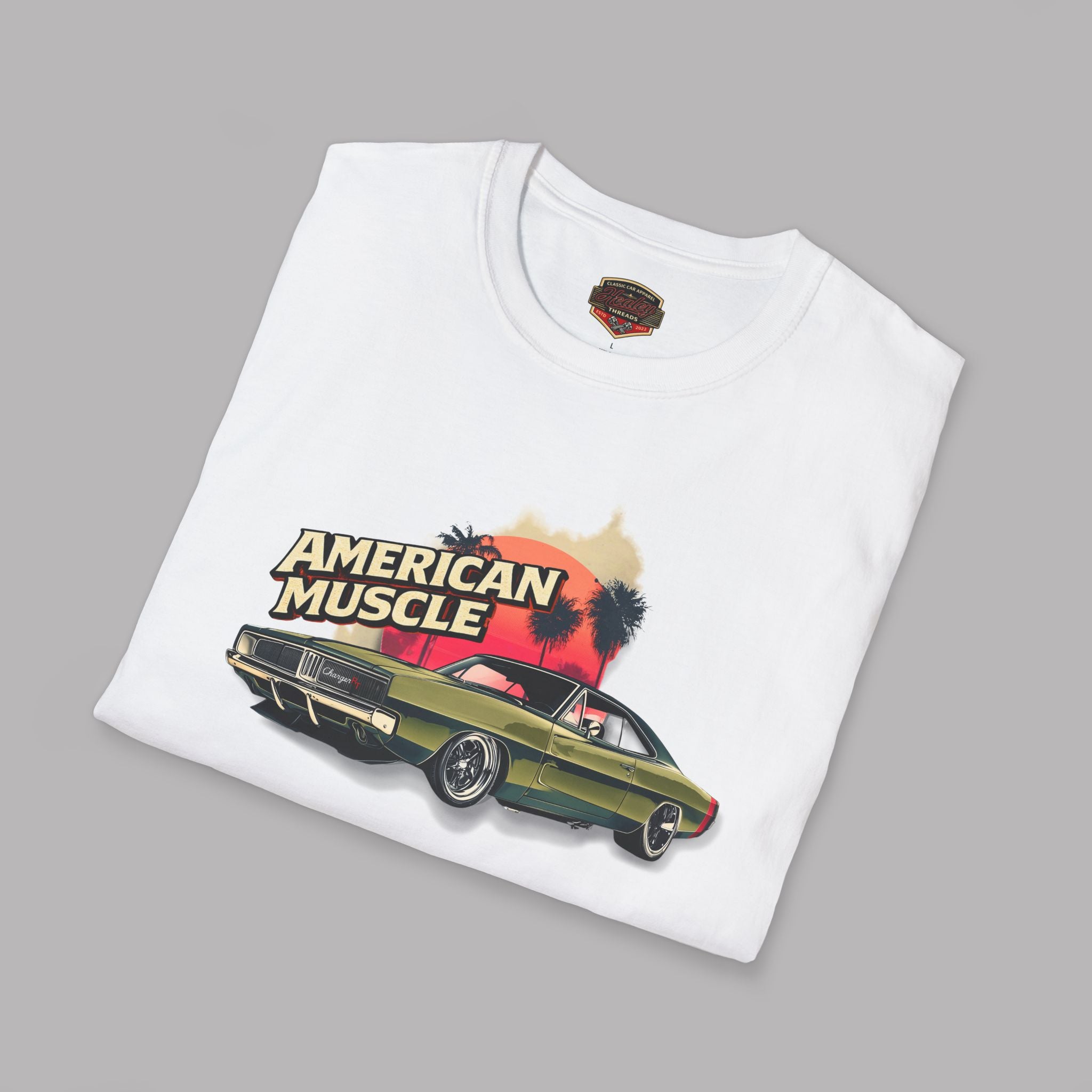 Folded white t-shirt with 'American Muscle' graphic design featuring a car and palm trees on a gray background