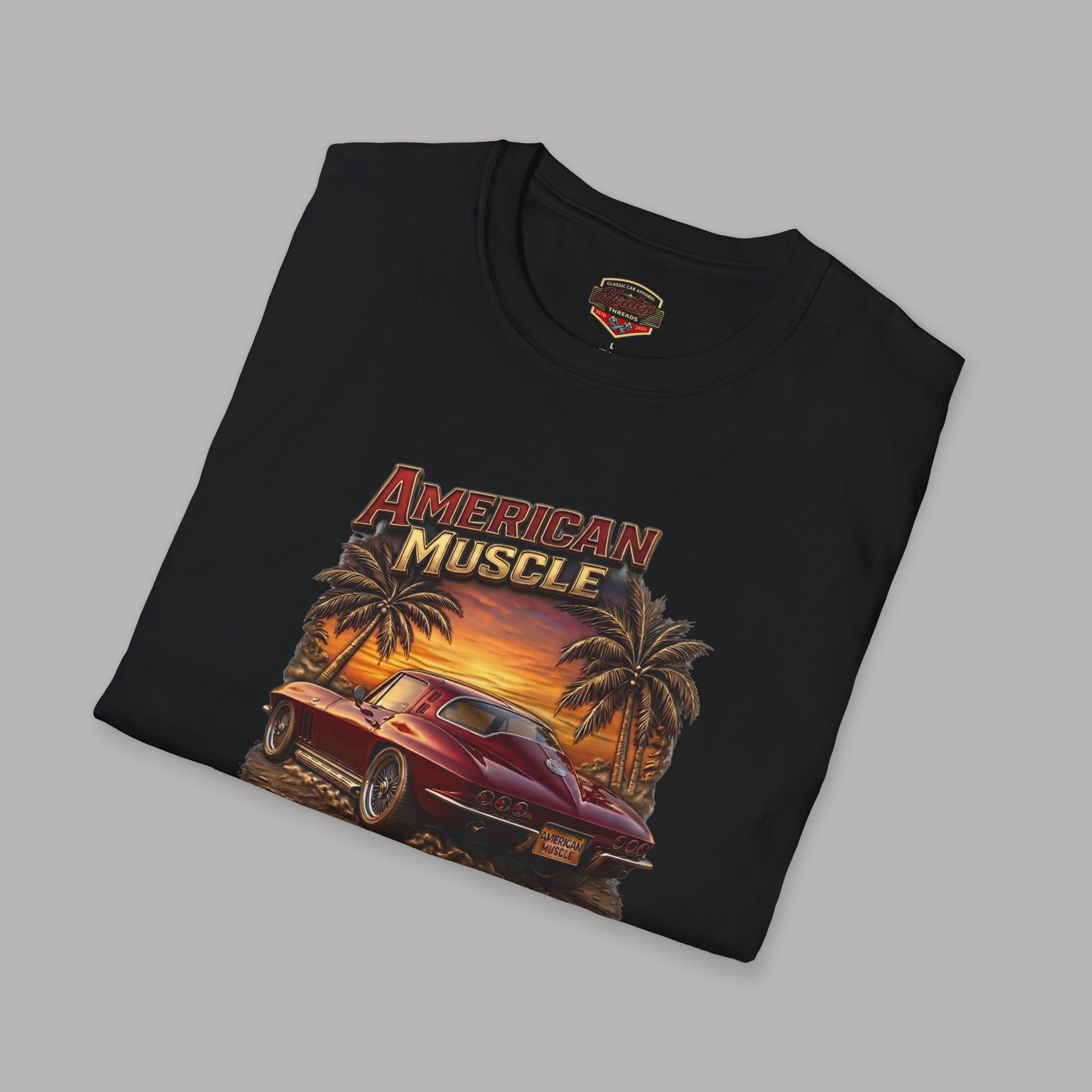 Folded black t-shirt with 'American Muscle' graphic design featuring a muscle car and palm trees on a gray background.