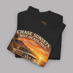 Folded black t-shirt with a classic red van and sunset design with text on a gray background