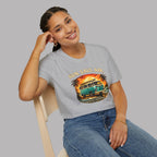 A woman wearing a light gray heather t-shirt with a retro graphic of a teal van bus and the text 'SUN, SALT, AIR.