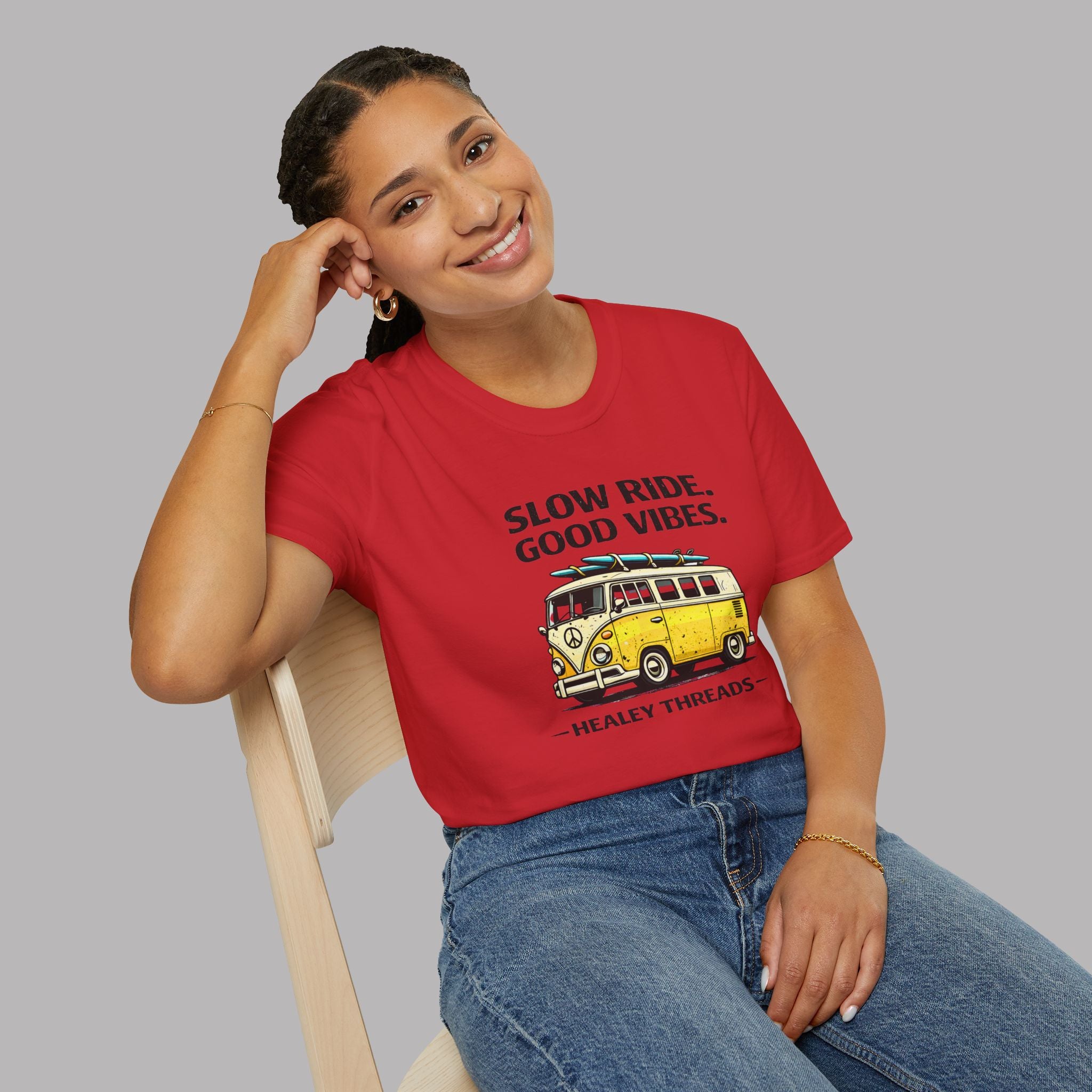 Woman wearing a red t-shirt with a graphic and text, sitting on a chair against a gray background
