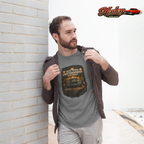 Man wearing a military green t-shirt with a graphic design and text, standing against a brick wall.