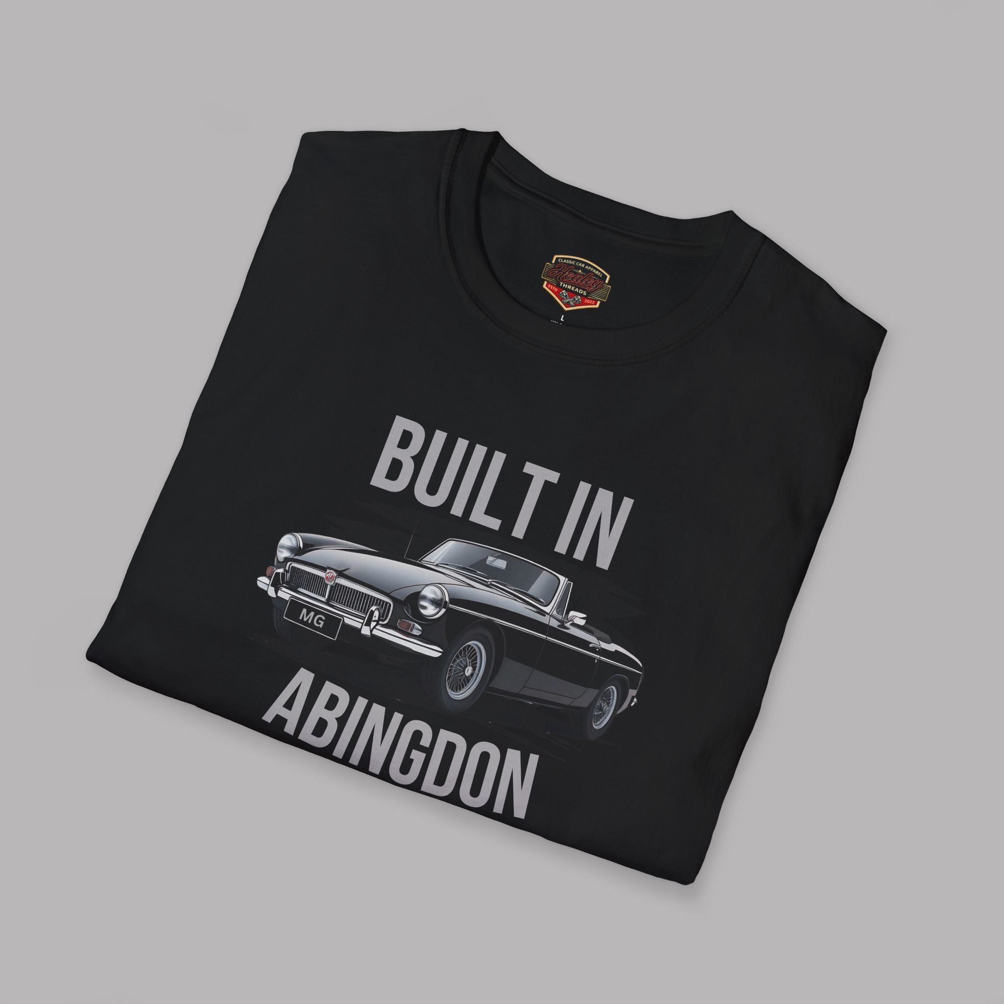 Folded black t-shirt with MGB car graphic and text 'Built in Abingdon' on a gray background