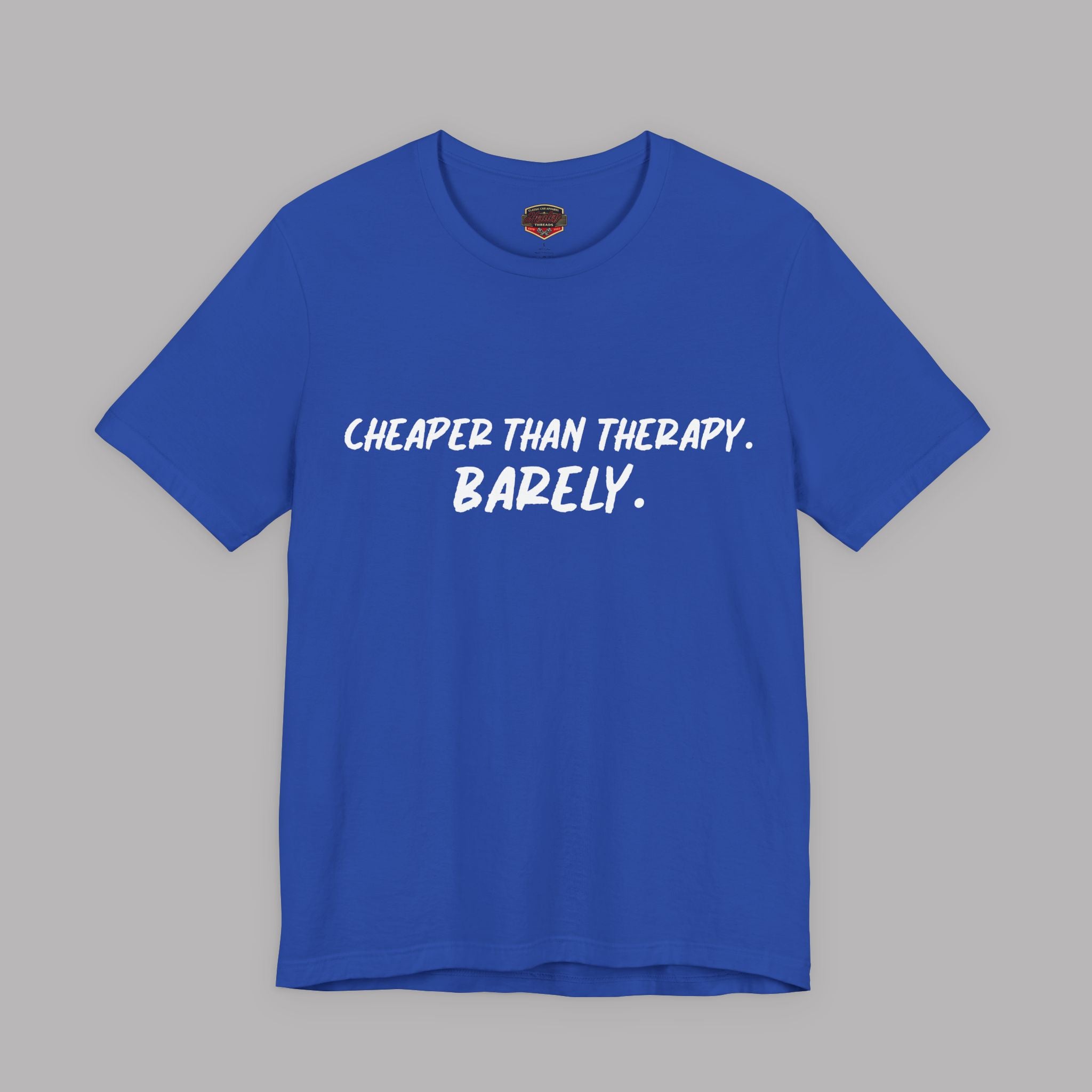 True blue t-shirt with white text "Cheaper than therapy. Barely." on a gray background
