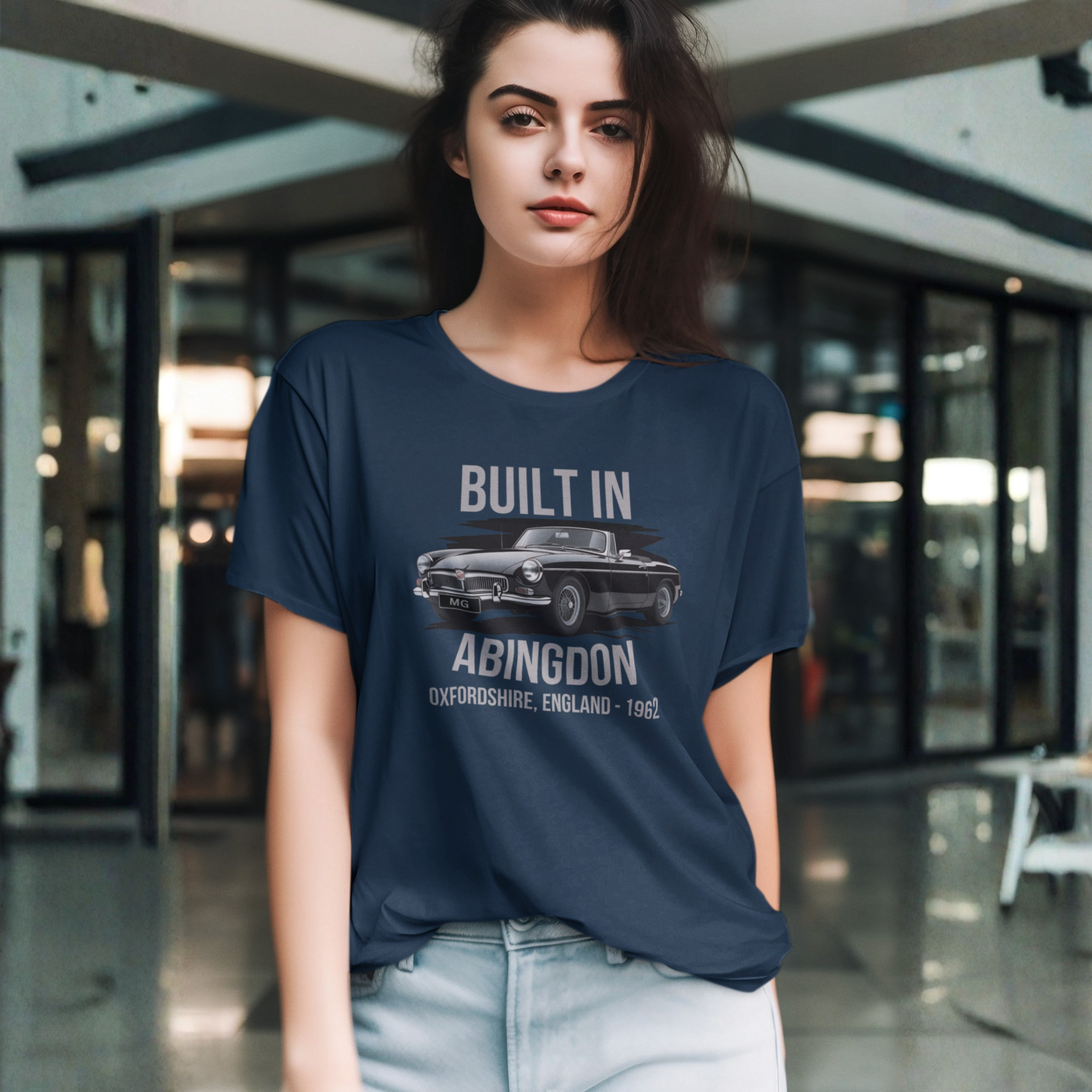 Woman wearing a navy blue t-shirt with a MGB car graphic and text in an indoor setting