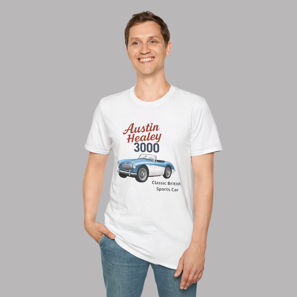 A man wearing a white graphic t-shirt with a vintage-style print of an Austin Healey 3000 sports car, paired with blue jeans, set against a solid gray background.