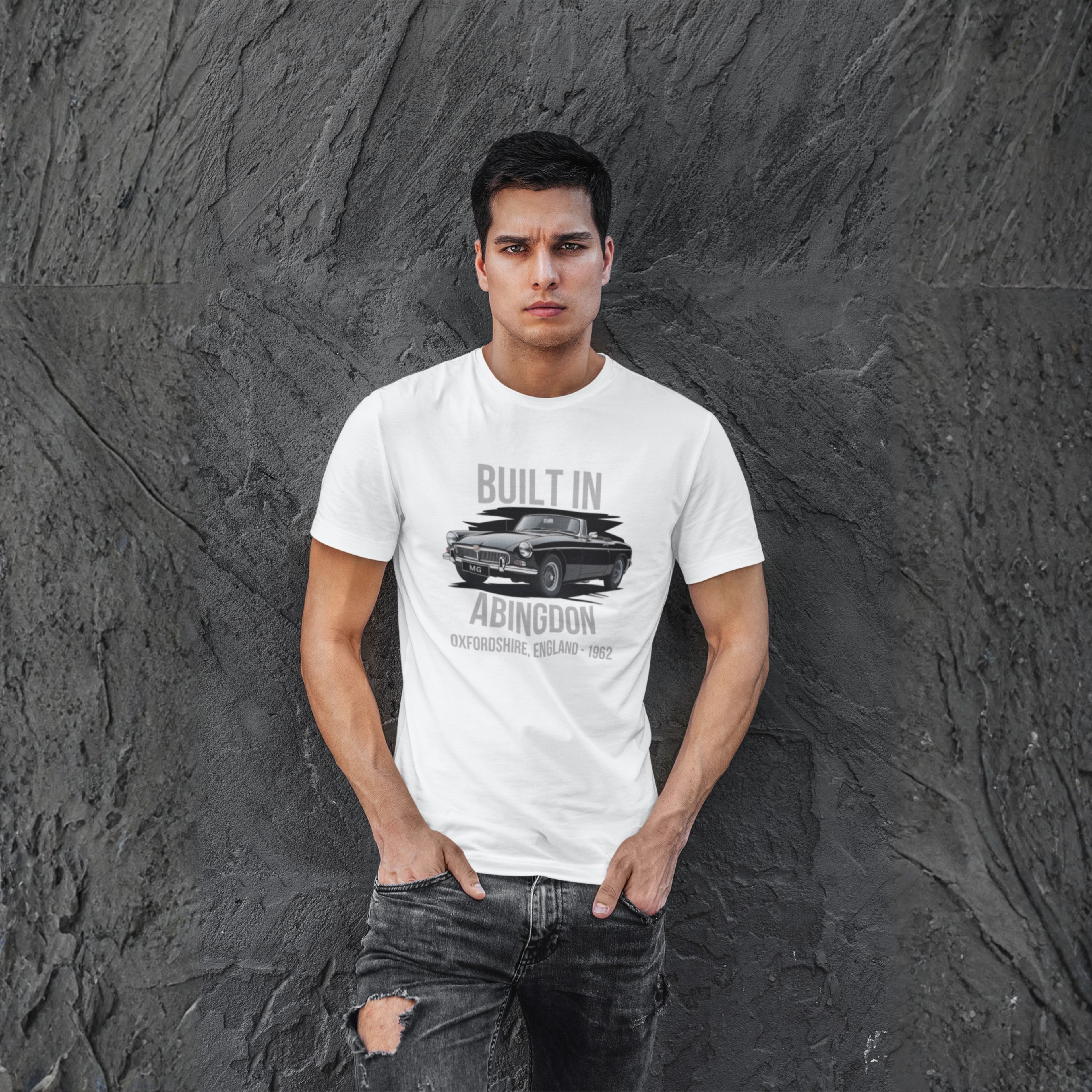 Man wearing a white t-shirt with a graphic MGB car design against a textured gray wall