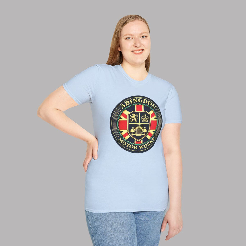 A woman modeling a light blue t-shirt with a circular 'Abingdon Motor Works' crest printed on the chest, set against a solid gray background.