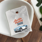 Folded white t-shirt with Austin Healey 3000 graphic on a white chair.