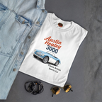 White t-shirt with Austin Healey 3000 graphic on a gray surface with denim jacket, sunglasses, and bracelets.
