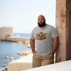 Man wearing a gray t-shirt with a logo by a coastal wall.