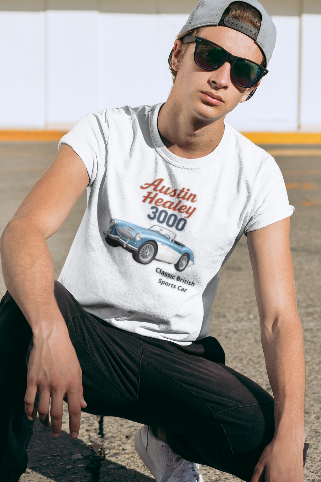 Man wearing a white t-shirt with an Austin Healey 3000 graphic, sitting outdoors.