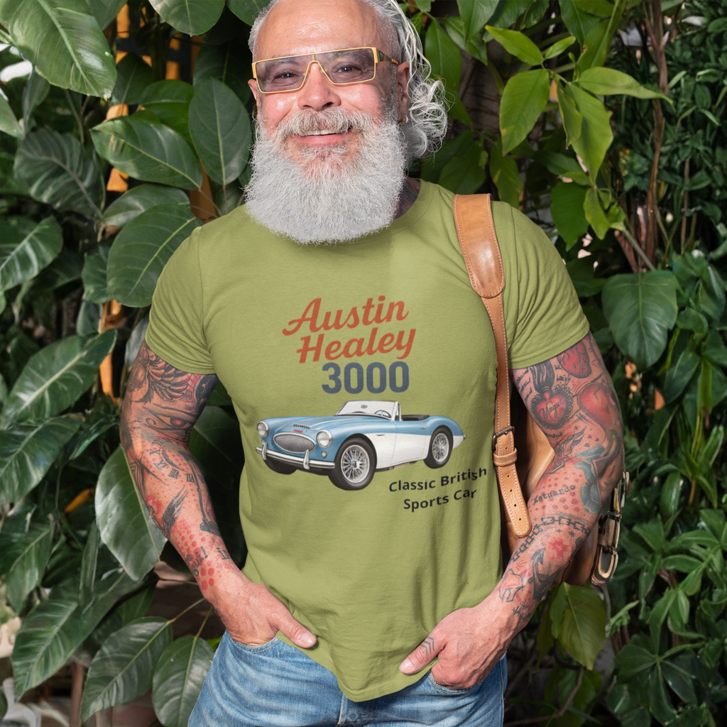 Man wearing a military green t-shirt with Austin Healey 3000 design, standing among green plants.